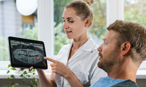 Dentist,Showing,And,Explaining,Dental,X-ray,Picture,With,Impacted,Wisdom
